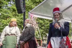 Liina Veskimägi-Iliste tutvustab oma Vigala kihelkonna rahvarõivakomplekti, taustal Margit Saarits Põltsamaa rõivastes ning Lembe Sihvre